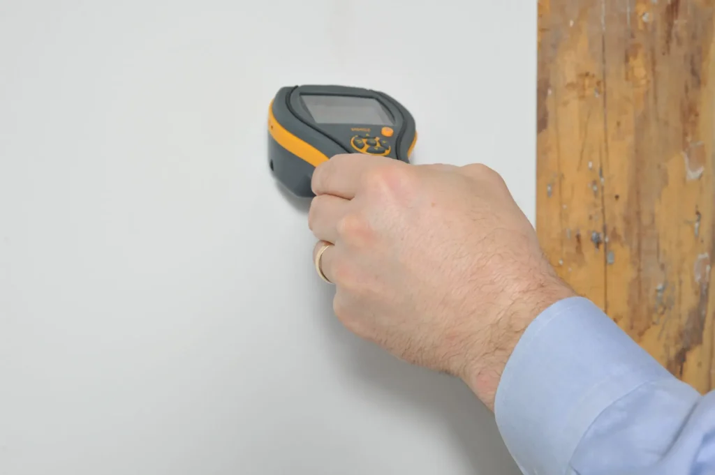 Professional using a moisture meter to check a wall for hidden mold and water damage