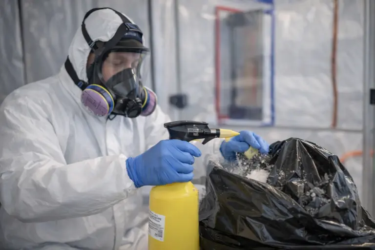 Black Mold Removal Services 3 “Certified black mold removal technician wearing protective gear safely spraying and sealing mold-contaminated debris during remediation.”