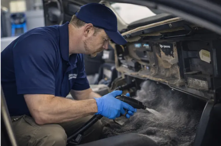 Vehicle Mold Remediation Services 1 “Professional vehicle mold removal technician cleaning mold contamination from a car’s interior dashboard and footwell area.”